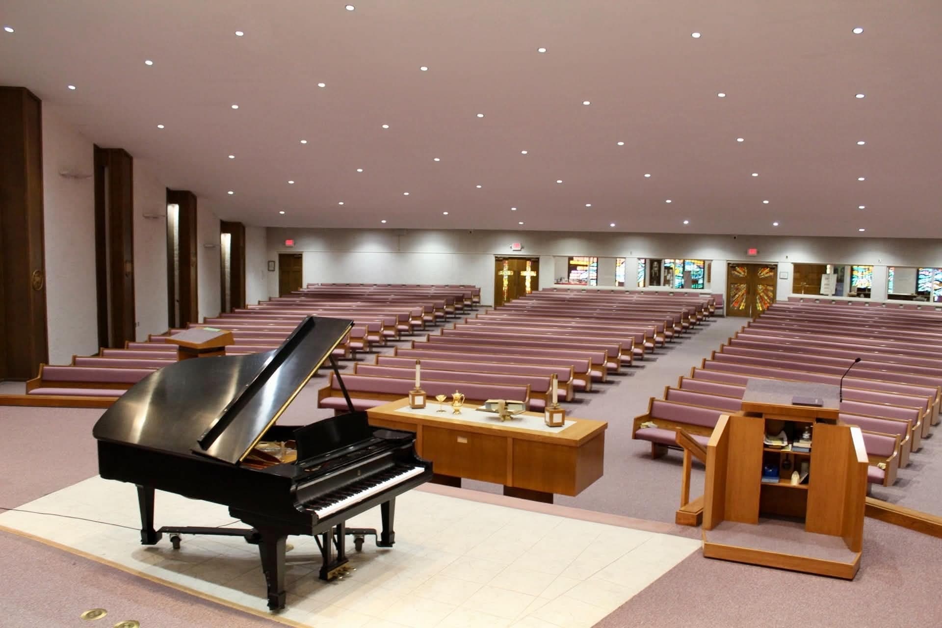 The sanctuary at Faith Presbyterian Church, with a black grand piano on the chancel and pews seating a thousand people.